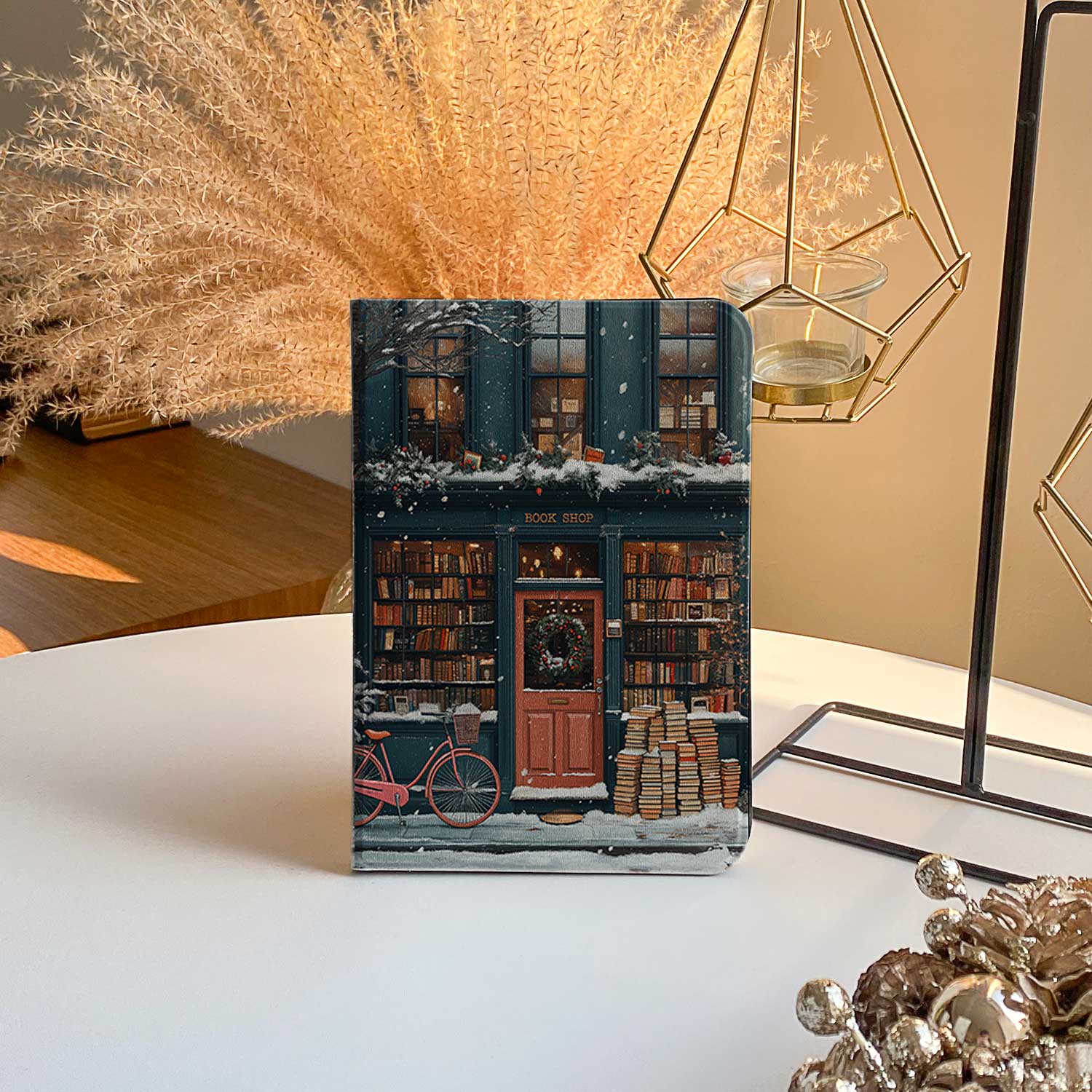 The ipad-pro-11-m4-case design features a bookstore in the snow with a red door and a black sign reading "Cherry." The store’s exterior and roof are covered in books, emphasizing its book-filled charm.