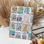 Notebook with travel-themed cover featuring city names and landmarks on a decorative surface.