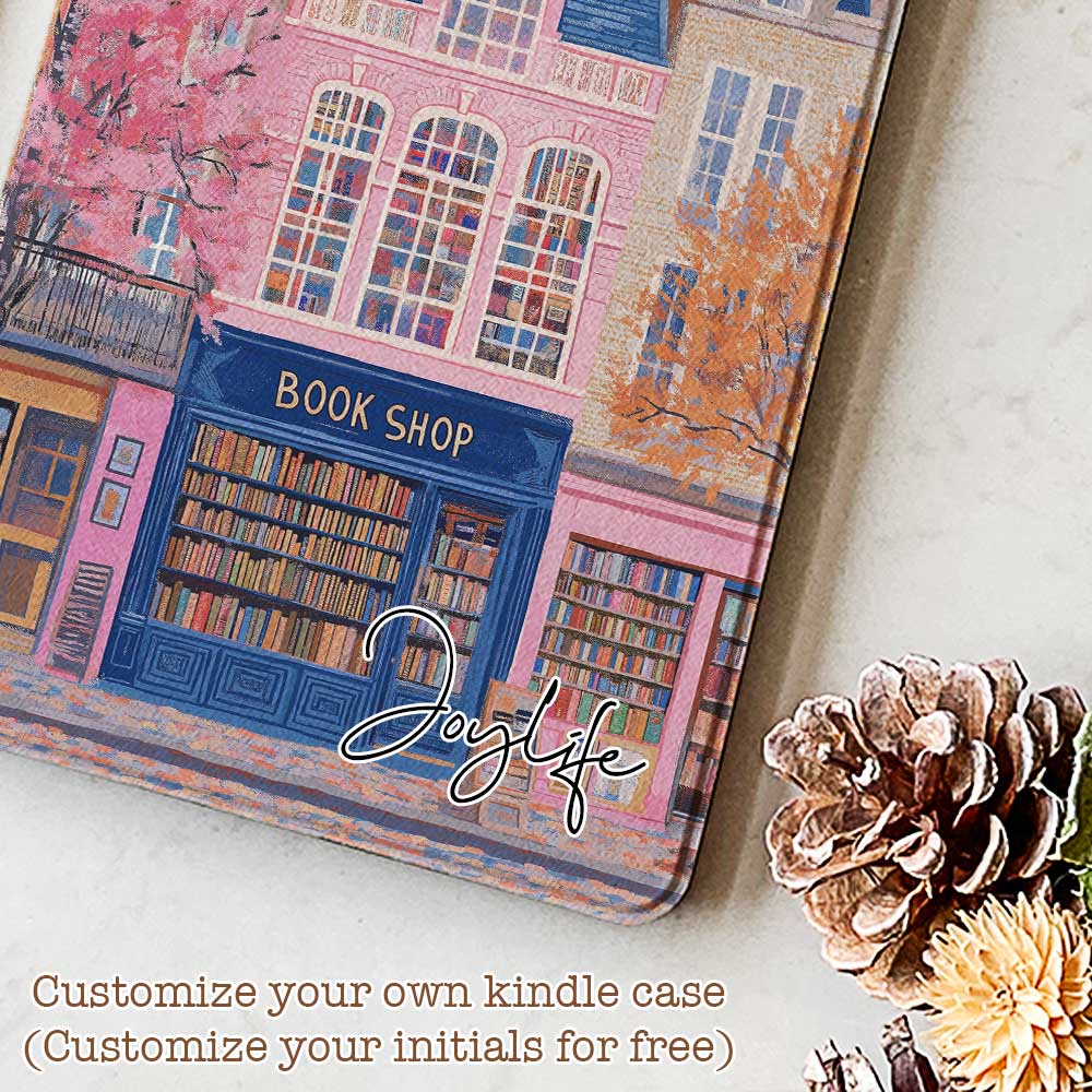 Design for a Kindle softcolor case featuring an illustration of a pink building with a blue roof and white-framed windows. In front, a bookshelf labeled 'BOOK SHOP' is displayed.