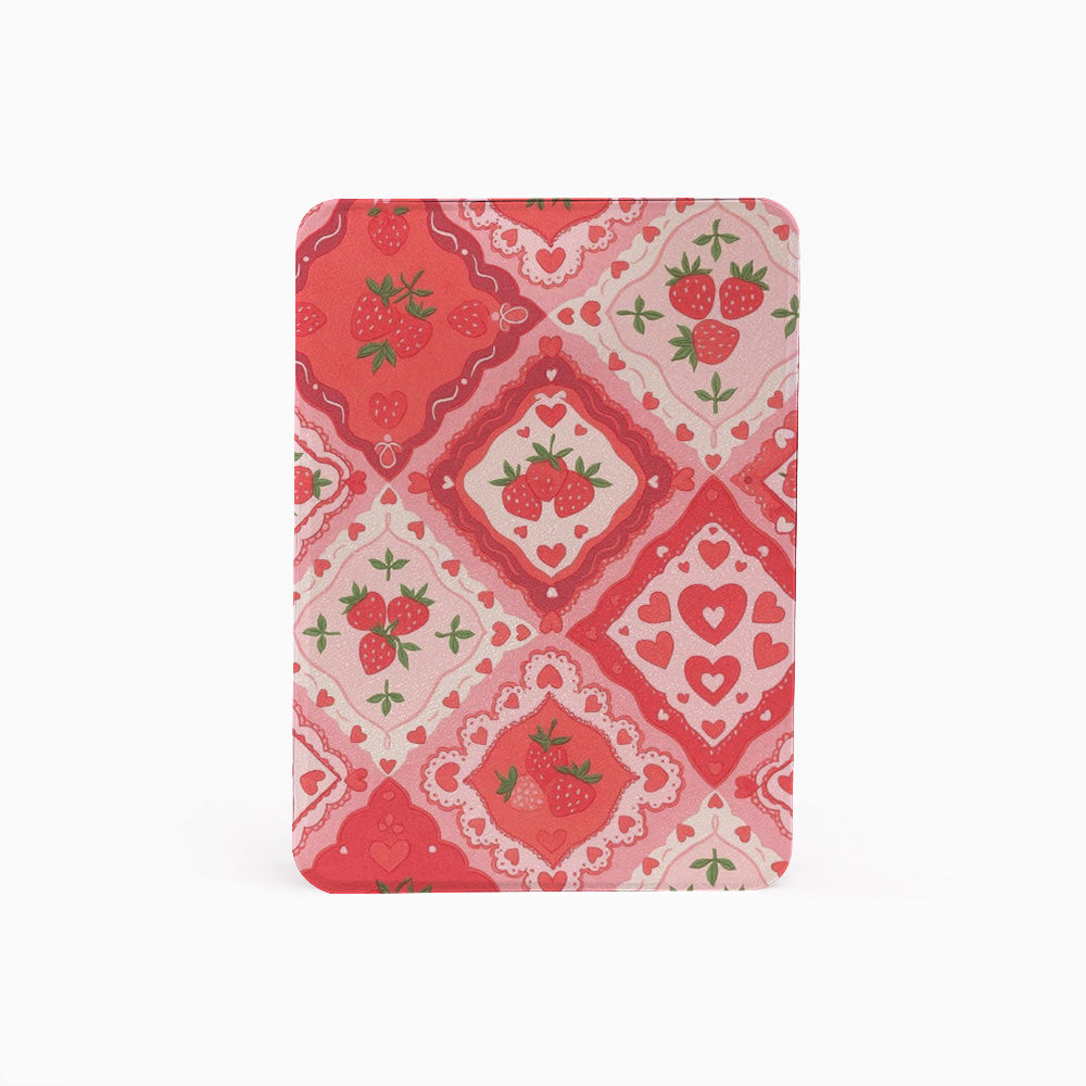 A rectangular notebook or journal with rounded corners, featuring a red and pink Valentine's Day themed pattern of strawberries, hearts, and floral tiles, shown on a plain white background.