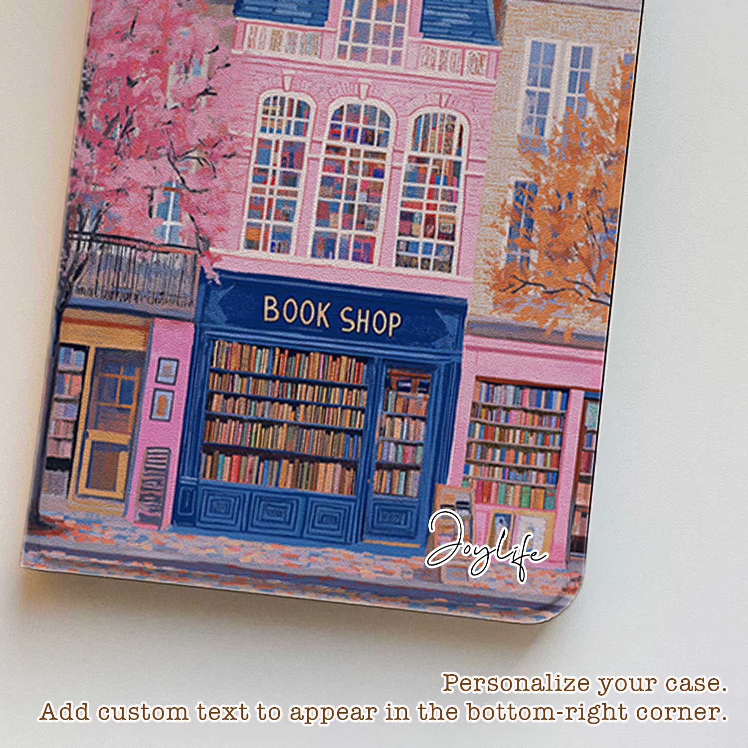 The iPad Pro M4 Case design features an illustration of a city street with vibrant buildings. The most prominent is a pink building in the center, labeled "BOOK SHOP." Large windows on the building display colorful bookshelves, creating an atmosphere full of knowledge and culture.