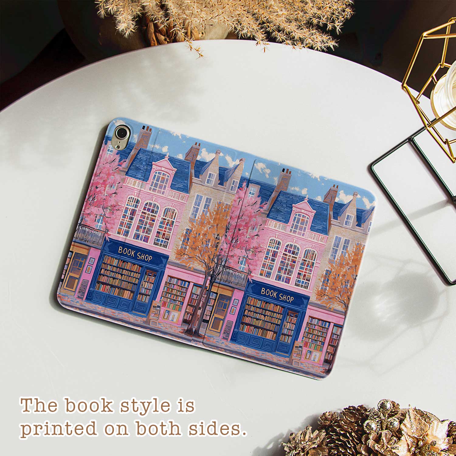 The iPad Pro M4 Case design features an illustration of a city street with vibrant buildings. The most prominent is a pink building in the center, labeled "BOOK SHOP." Large windows on the building display colorful bookshelves, creating an atmosphere full of knowledge and culture.