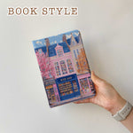 The iPad Pro M4 Case design features an illustration of a city street with vibrant buildings. The most prominent is a pink building in the center, labeled "BOOK SHOP." Large windows on the building display colorful bookshelves, creating an atmosphere full of knowledge and culture.