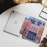 The iPad Pro M4 Case design features an illustration of a city street with vibrant buildings. The most prominent is a pink building in the center, labeled "BOOK SHOP." Large windows on the building display colorful bookshelves, creating an atmosphere full of knowledge and culture.